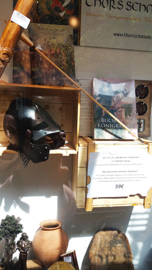 Schaufenster des Ladengeschäfts 'Thors Schmiede' mit Das Buch der Königreiche in der Auslage.